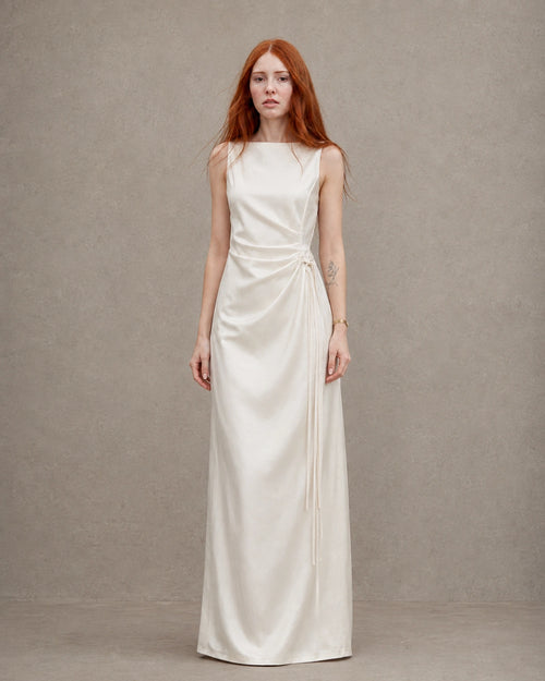 Woman wearing an apricot tencel-linen fitted dress with a high waist seam and side tie detail, shown from the front.