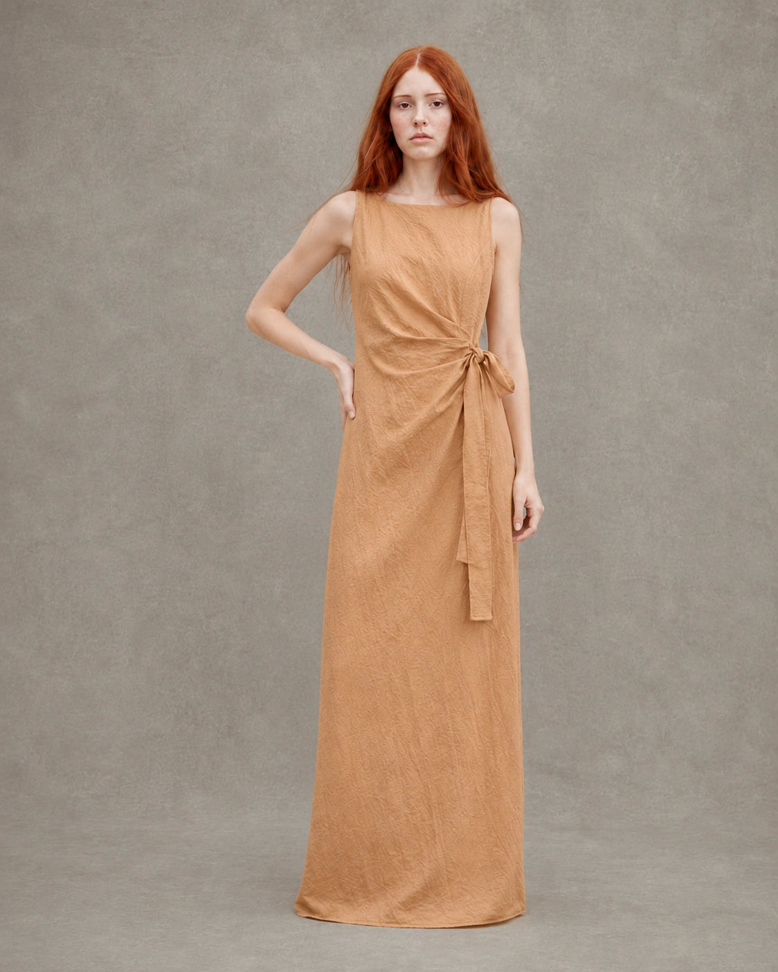 Back view of an orange tencel-linen fitted dress with a fitted A-line skirt, shown on a model.