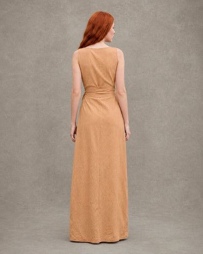 Close-up of the gathered waist and fabric tie on an orange tencel-linen dress, shown on a model.