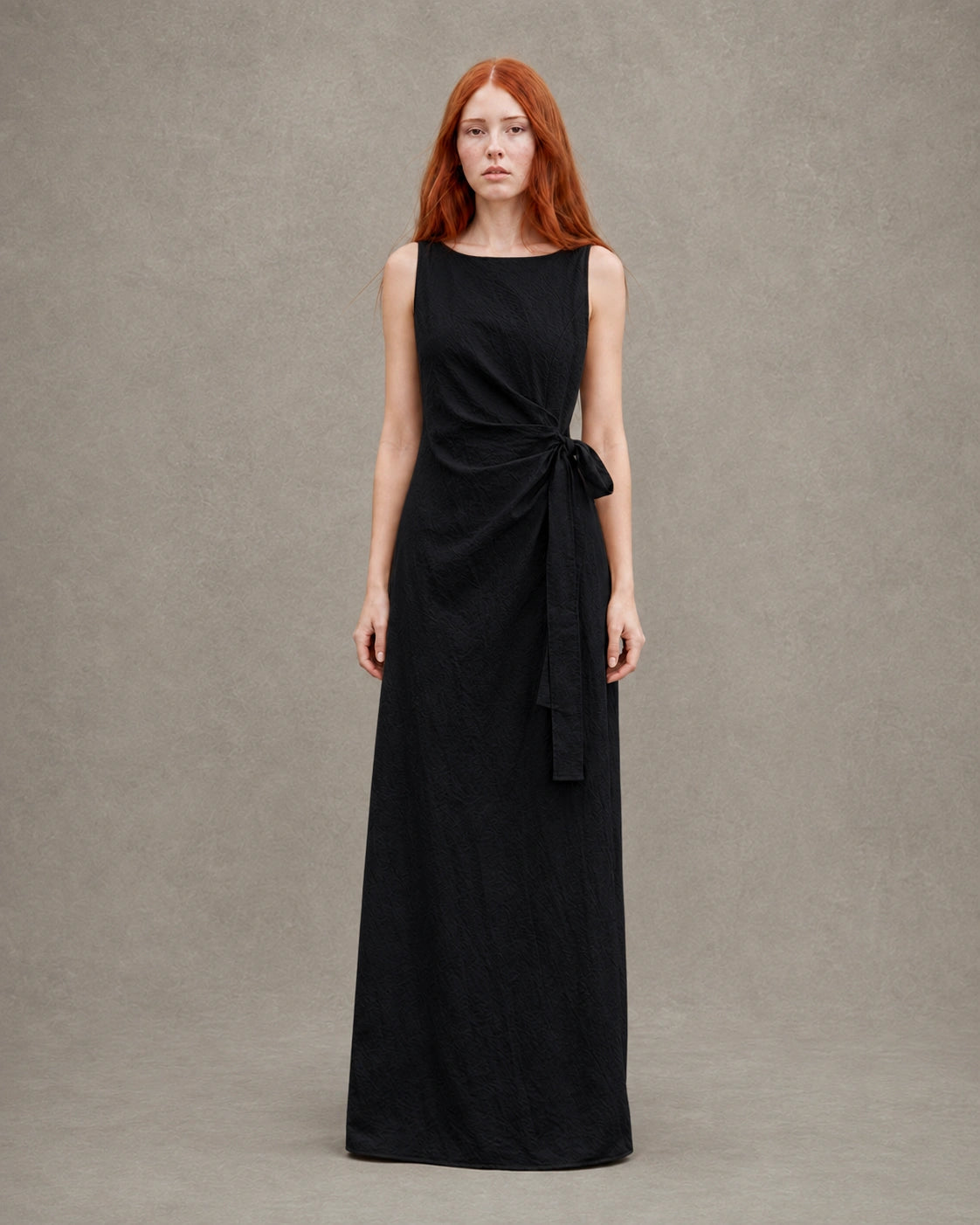 Woman wearing a black tencel-linen fitted dress with a high waist seam and side tie detail, shown from the front.