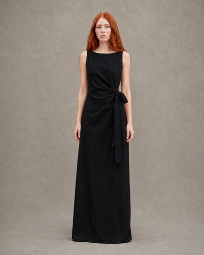 Woman wearing a black tencel-linen fitted dress with a high waist seam and side tie detail, shown from the front.
