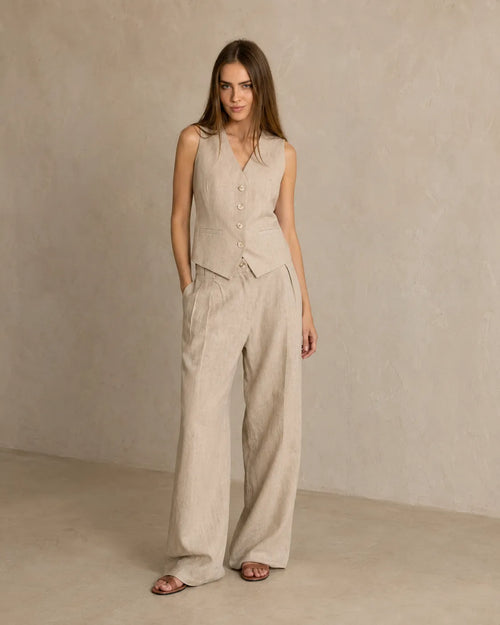 Een model draagt de kaki mouwloze top en wijde broek, met één hand in haar zak.
