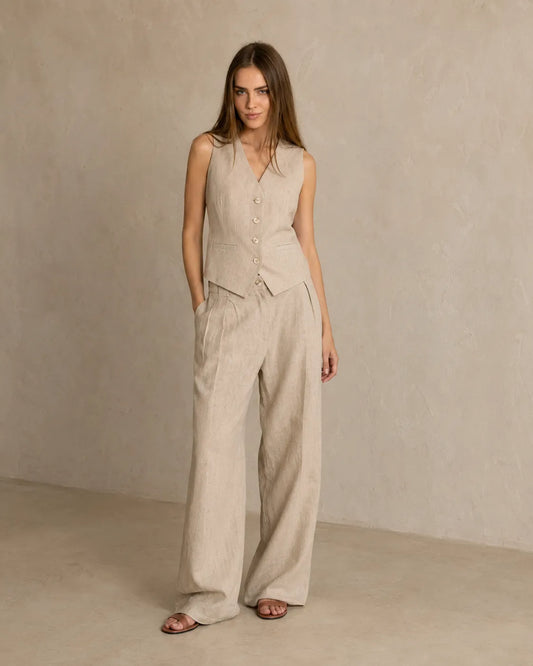 Een model draagt de kaki mouwloze top en wijde broek, met één hand in haar zak.