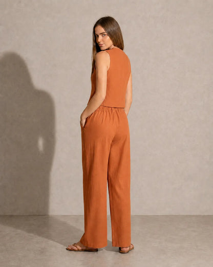 Achteraanzicht van een model in de oranje co-ord set, met zicht op de taillelband van de broek met lage taille.