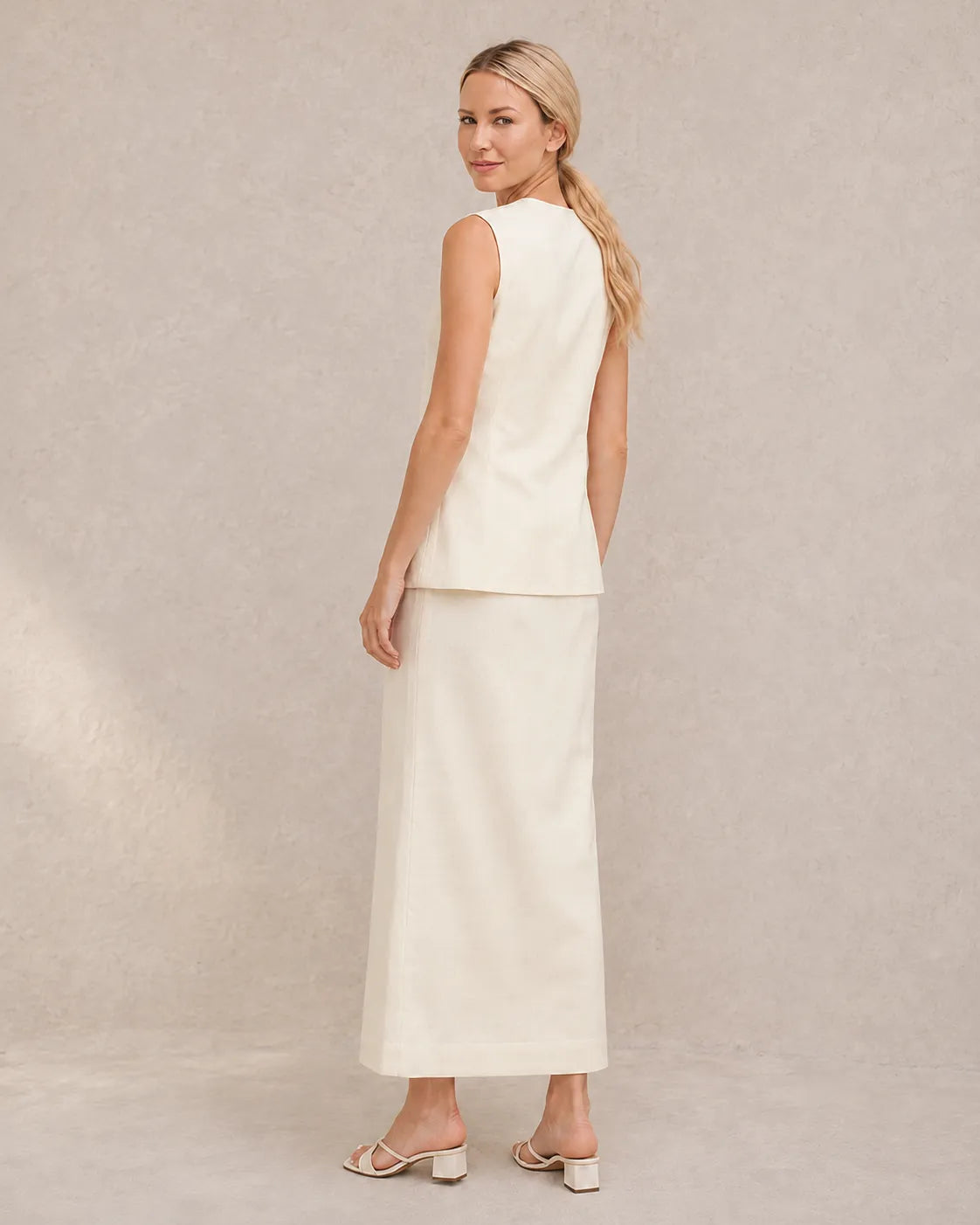 Achteraanzicht van een model in de gebroken witte co-ord set, met zicht op de taillelband van de rok met hoge taille.