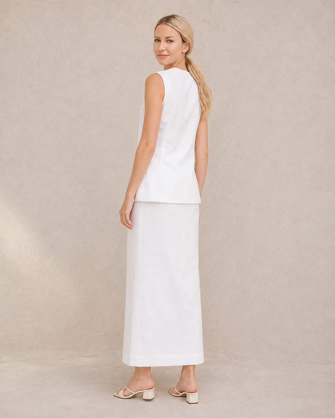 Achteraanzicht van een model in de witte co-ord set, met zicht op de taillelband van de rok met hoge taille.
