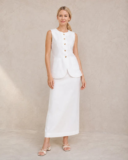 Een model draagt de witte mouwloze top en hoge taille maxirok, staand in een ontspannen vooraanzicht.