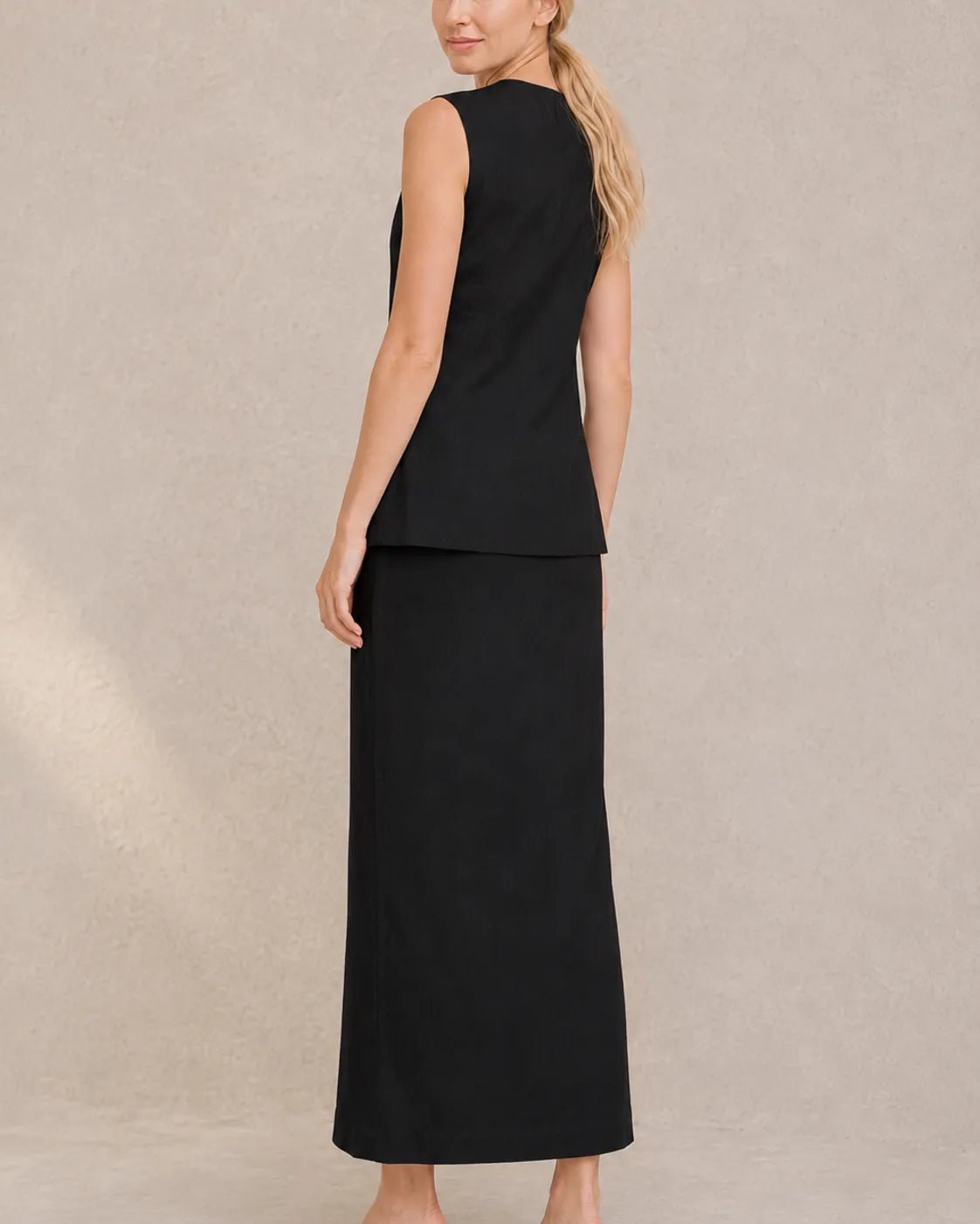 Achteraanzicht van een model in de zwarte co-ord set, met zicht op de taillelband van de rok met hoge taille.